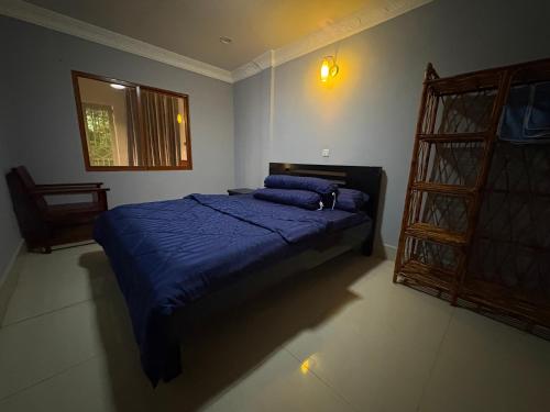 a bedroom with a bed with blue sheets and a window at Wheelezz in Kep