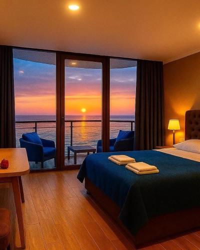 a bedroom with a bed and a view of the ocean at Panorama Kvariati in Kvariati