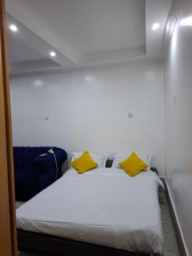a bed in a small room with yellow pillows at Pivot Studio near Westside mall in Nakuru
