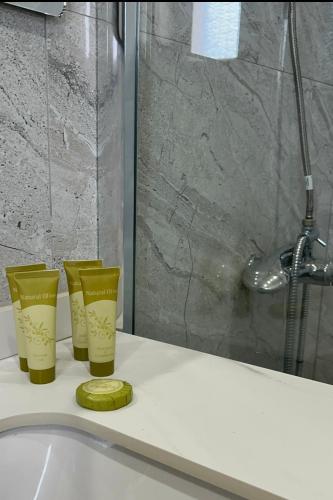 a bathroom sink with three cups and a shower at Kiki's Rooms 2 in Vlorë