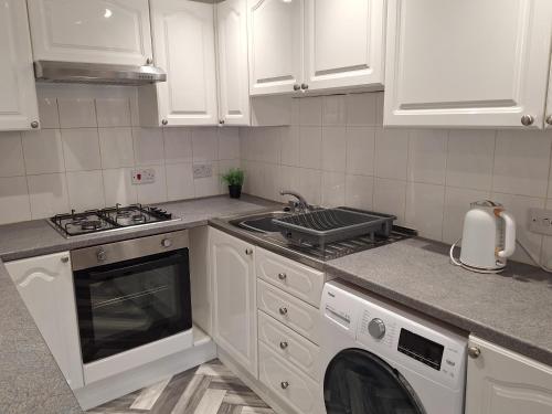 a kitchen with white cabinets and a stove and a sink at Old Coach House Apartment with Garage in Scarborough