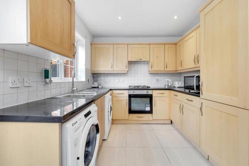 a kitchen with wooden cabinets and a white dishwasher at The ground floor Green Oasis, near the station in London