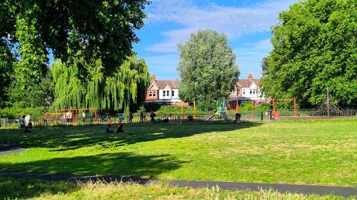 a park with people playing in the grass at The ground floor Green Oasis, near the station in London