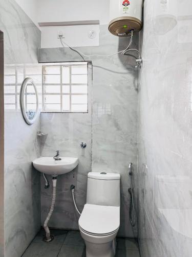 a white bathroom with a toilet and a sink at SHR Comfort Near Reva Circle Yelahanka in Bangalore