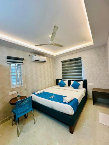 a bedroom with a large bed and a blue chair at SHR Comfort Near Reva Circle Yelahanka in Bangalore