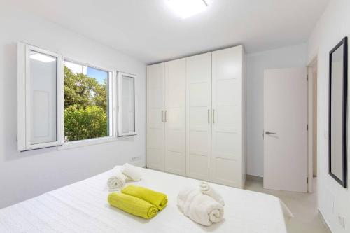 a white bedroom with white cabinets and yellow towels on a bed at Villa Mare a fabulous hideaway in S'Algar