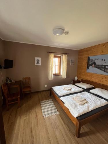 a bedroom with two beds and a table and a window at Wellness hotel - Viktorka, herecký dům in Česká Skalice