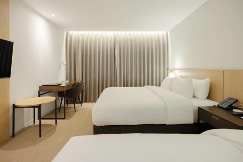 ein Hotelzimmer mit zwei Betten und einem Schreibtisch in der Unterkunft Anook Signature Hotel Incheon Guwol in Incheon