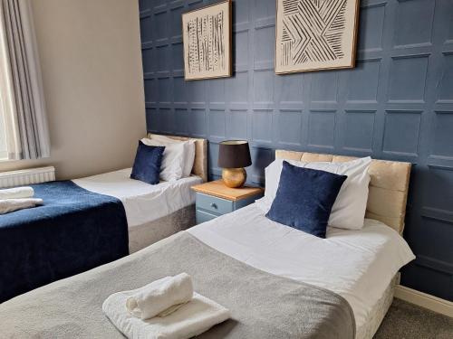 two beds in a room with blue walls at The Hampton Beautiful 3 Bedroom House with Conservatory & Garden in Scarborough