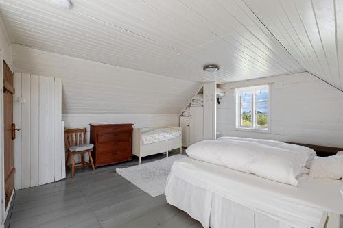 a white bedroom with a bed and a window at Kartveit Gjestetun in Manger