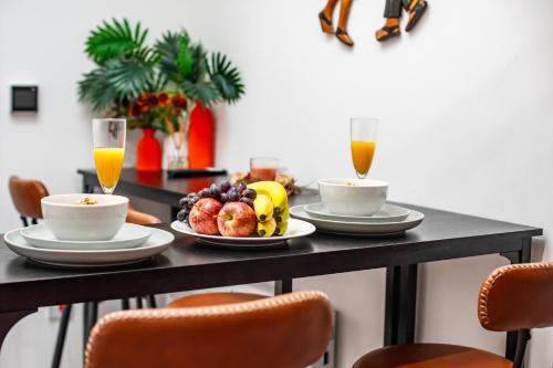 a table with plates of fruit and two glasses of orange juice at Tambo Apartments in London