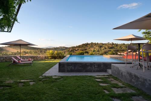 a swimming pool with chairs and umbrellas in a yard at Casa Dr Ramiro Salgado - Douro Superior, Torre de Moncorvo in Torre de Moncorvo