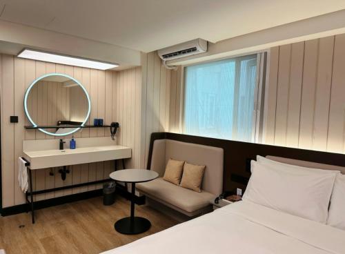 a bedroom with a bed and a sink and a mirror at Hanting Hotel Guangzhou Tianhe in Guangzhou