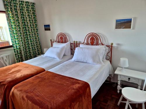 a bedroom with two beds and a table and a window at Caparica for Rent in Costa da Caparica