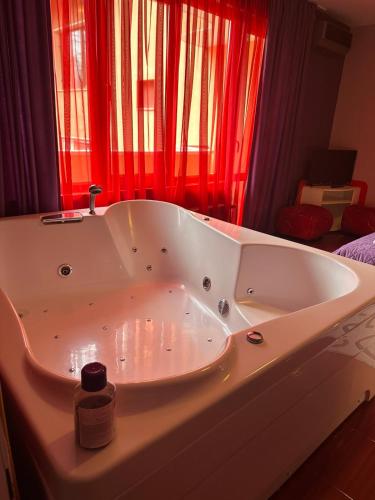 a large white bath tub in a room with red curtains at Gelov Hotel in Berkovitsa