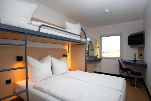 a bedroom with two bunk beds and a desk at Magnet Hotel in Schkeuditz