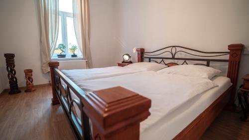 a bedroom with a bed with white sheets and a window at Peony Apartment in Kroměříž