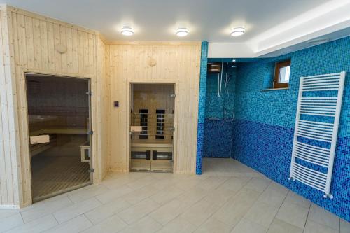 a bathroom with blue tiled walls and a shower at Private Vendégház in Villány