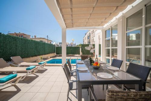 a patio with a table and chairs and a pool at Villa Savina by BeBreeze in Can Picafort