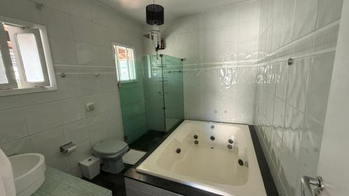 a white bathroom with a tub and a toilet at BC Bier Hostel in Balneário Camboriú