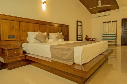 a bedroom with a large bed with a wooden headboard at Villa Sanchana in Galle