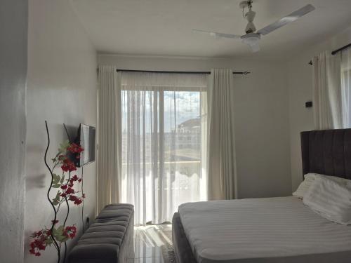 a bedroom with a bed and a large window at Furahi Apartment in Mombasa