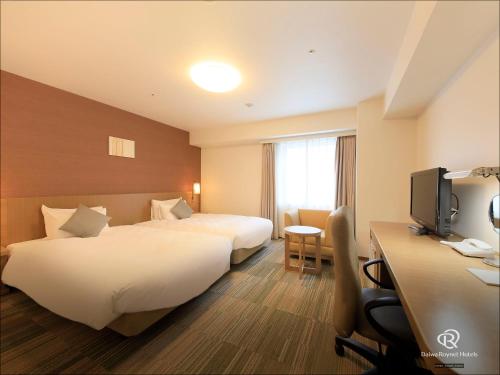 a hotel room with two beds and a desk at Daiwa Roynet Hotel Sakai Higashi in Sakai