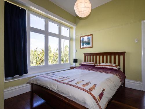 a bedroom with a bed and a large window at Oroua Cottage - Rangataua Bach in Ohakune