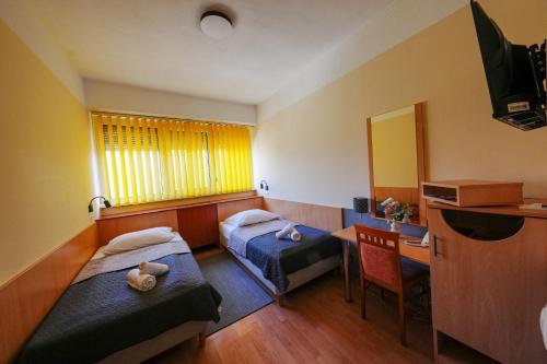 a room with two beds and a desk and a television at Sport Hotel in Debrecen