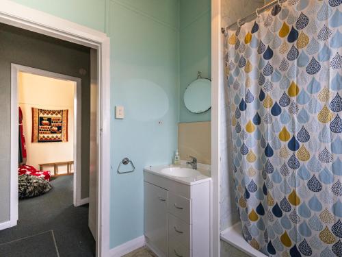 a bathroom with a sink and a shower curtain at Oroua Cottage - Rangataua Bach in Ohakune