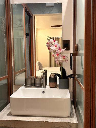 a bathroom sink with a mirror and flowers on it at Calathea Suites El Nido in El Nido