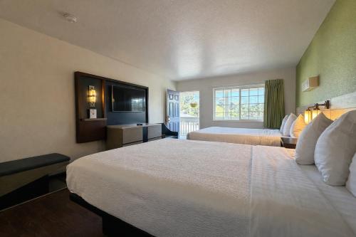 a hotel room with two beds and a television at Fisherman's Cove Inn in Monterey