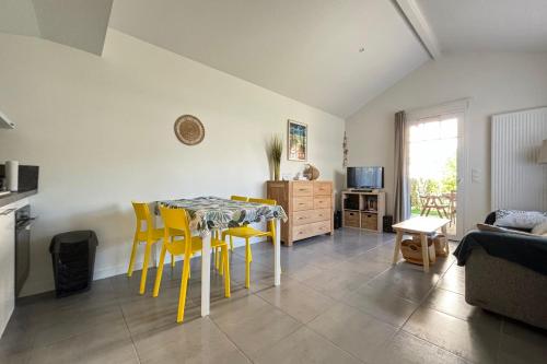 a living room with a table and yellow chairs at Air-conditioned house in the Arcachon style with swimming pool in La Teste-de-Buch