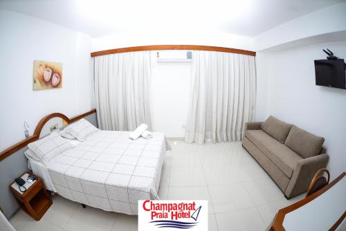 a small bedroom with a bed and a couch at Champagnat Praia Hotel in Vila Velha