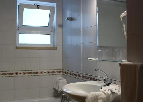 a white bathroom with a sink and a window at Hotel Santo Antonio Da Baia in São Martinho do Porto