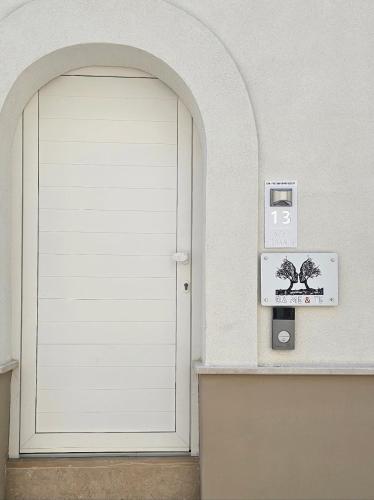 a white door in a white wall with a clock at Da Me & Te in Ginosa