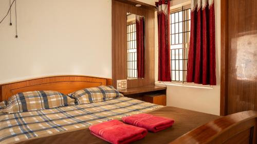 a bedroom with a bed with two red pillows on it at DUDI's Stay in Mysore