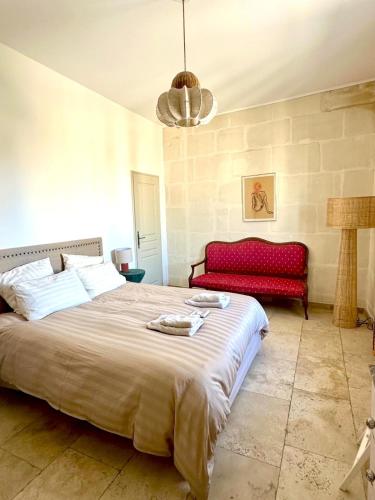 a bedroom with a large bed and a red couch at Appartement aux Arènes in Arles