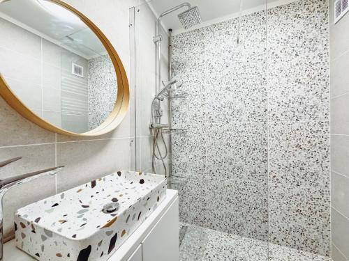 a bathroom with a shower with a sink and a mirror at Kodó Apartman in Székesfehérvár