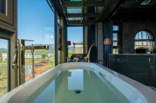 a bath tub in a room with a large window at Zishui Qinglu Manor in Sanya