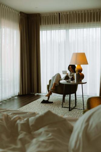 a woman sitting at a table in a hotel room at Garden Suites - Duinhotel in Burgh-Haamstede zeeland in Burgh Haamstede