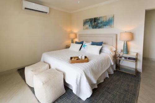 a bedroom with a white bed with a suitcase on it at 102 Lighthouse Bay Barbados in Christ Church