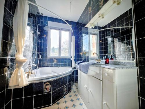a blue tiled bathroom with a tub and a sink at Vaucorbe - Bail Partner in Roffey