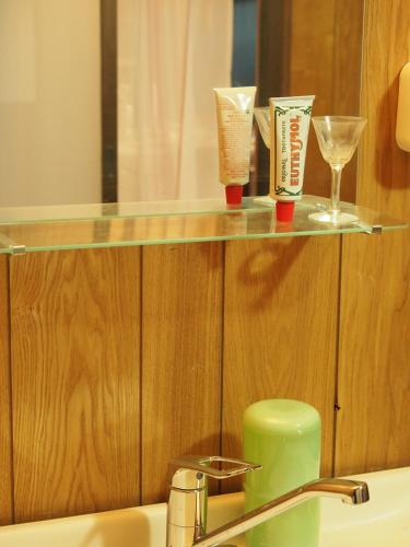 a bathroom with a sink and a shelf with glasses at Riad Camellia in Mitoyo