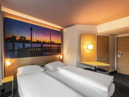 a bedroom with a bed with a painting on the wall at B&B Hotel Düsseldorf-City in Düsseldorf