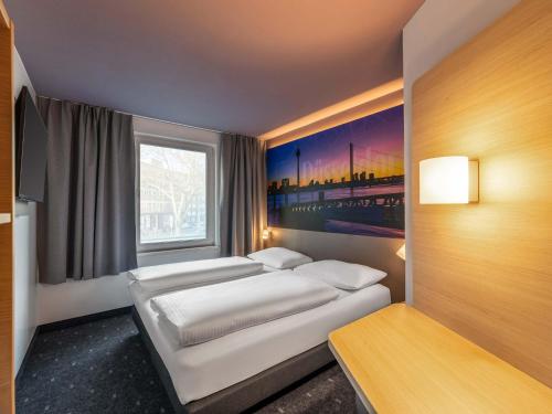 a bedroom with a white bed and a window at B&B Hotel Düsseldorf-City in Düsseldorf