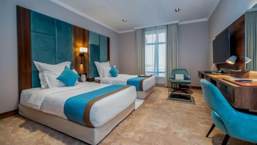 a hotel room with two beds and a desk at Madareem Hotel in Riyadh