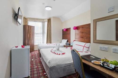 a hotel room with two beds and a desk at Lucky 8 Hotel in Ilford