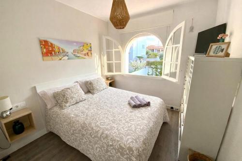 a small bedroom with a bed and two windows at Piscina privada de Sal, Cala Canyadell in Torredembarra