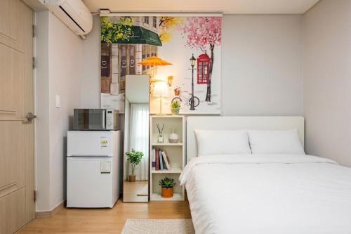 a bedroom with a white bed and a refrigerator at Ara Guesthouse in Busan
